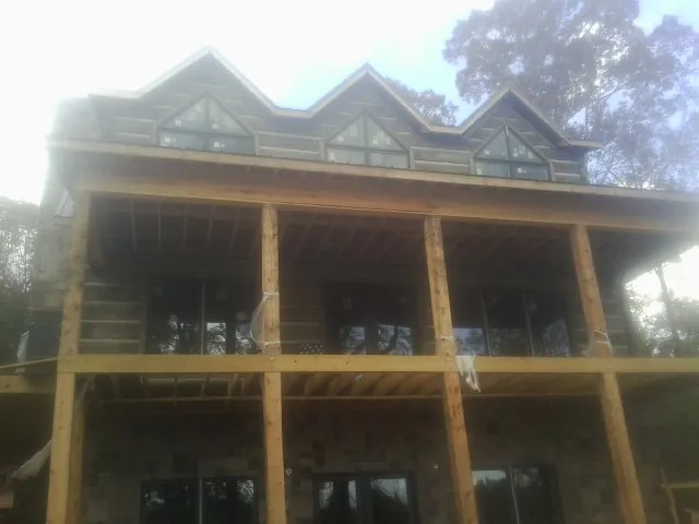 Dormers and porch framing on a large log home under construction — Roof Coating work by our crew in Orfordville