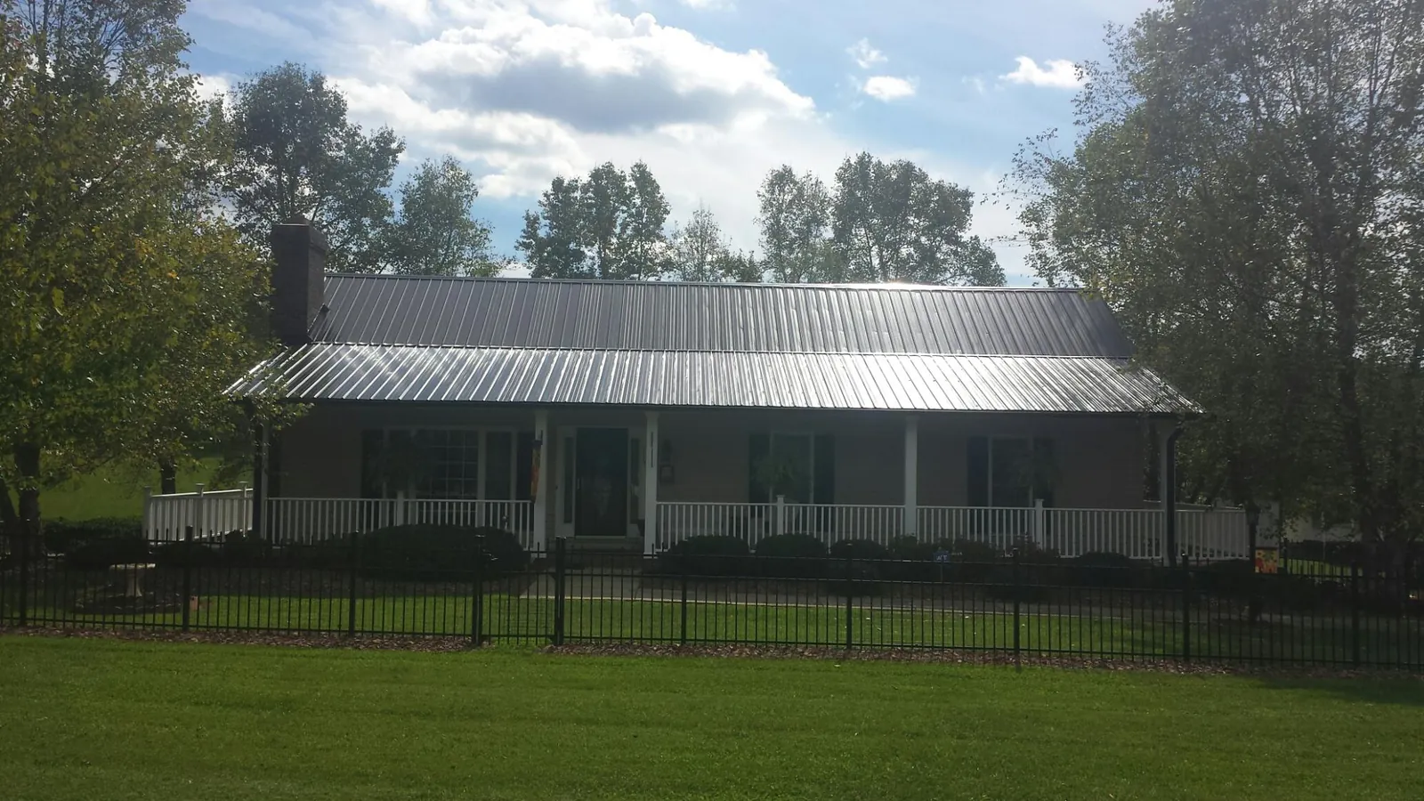 Gray metal roof on a brick ranch with a full width front porch — Gutter Guard Installation work by our crew in Orfordville