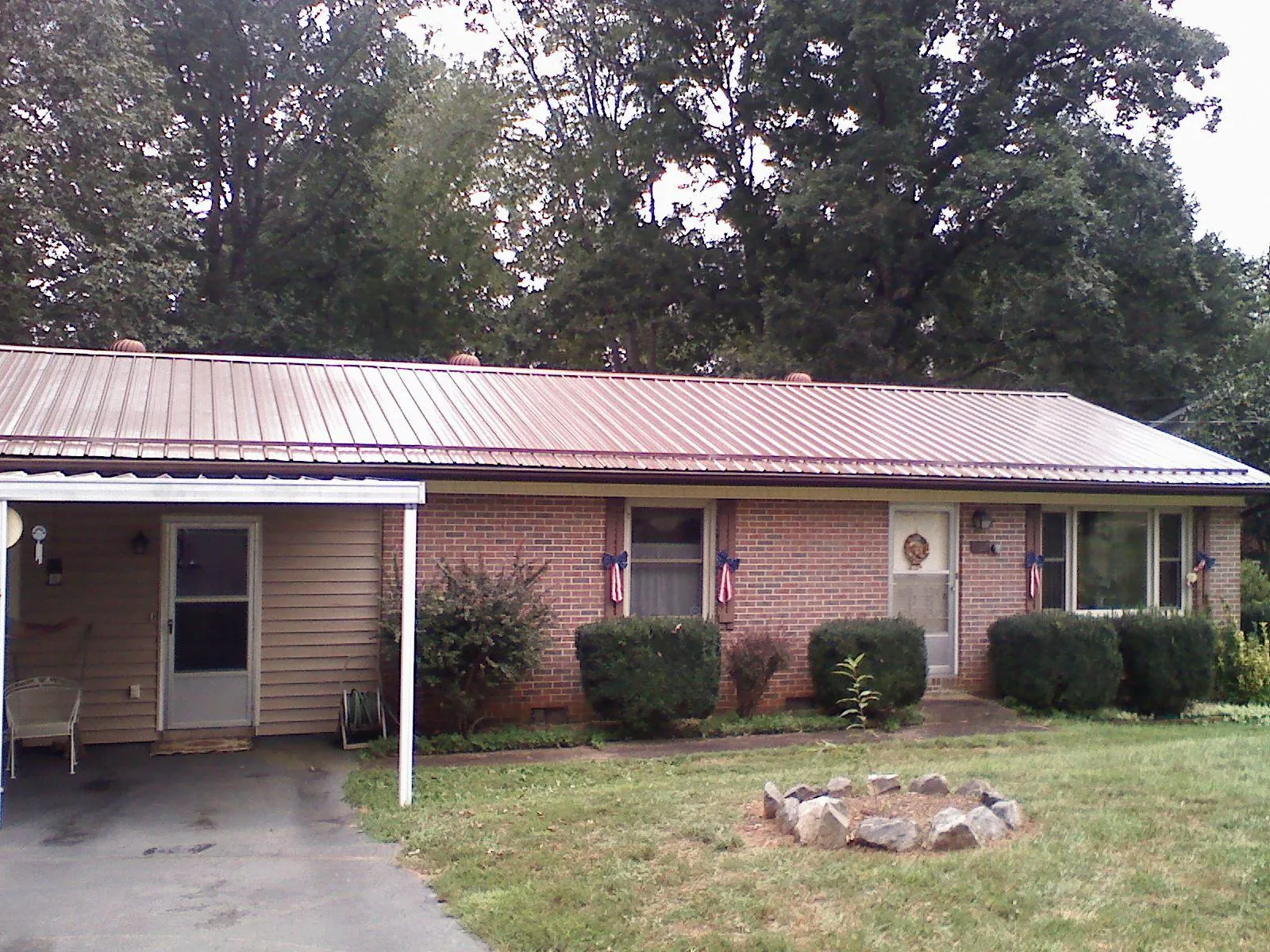 Bronze metal roof and carport on a brick ranch home — Roof Repair work by our crew in Orfordville