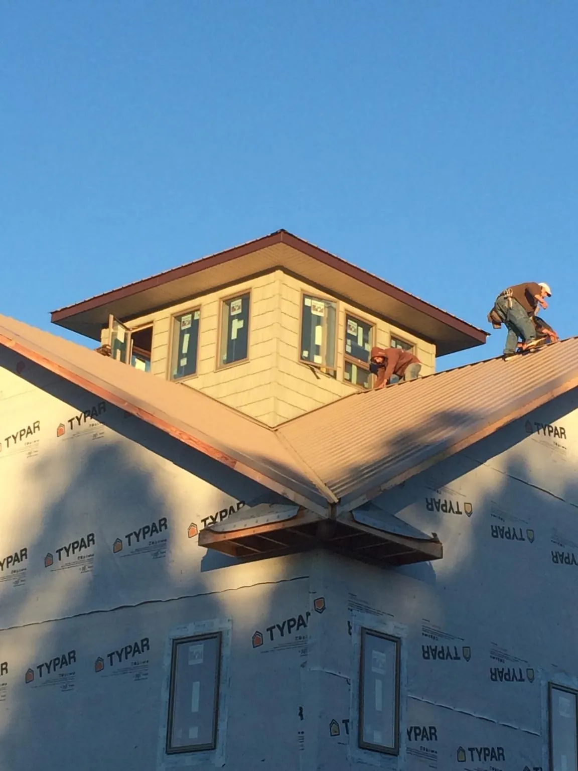 Roofers working around a rooftop cupola on a new metal roof at sunset — Roof Waterproofing in Orfordville by Roofing Brothers